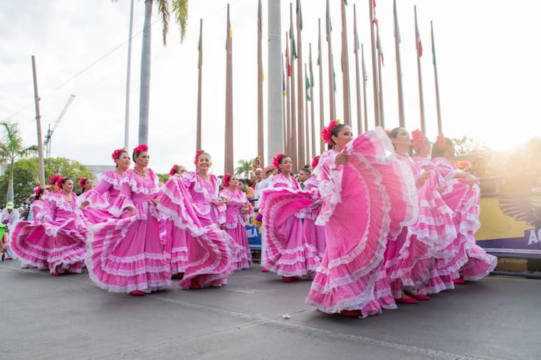 Integrantes de la comparsa Pilón Rosa con vestidos rosados y el mensaje "Danzando por la Vida - Fundación Madrina Rosa" en una pancarta, durante el Festival de la Leyenda Vallenata.