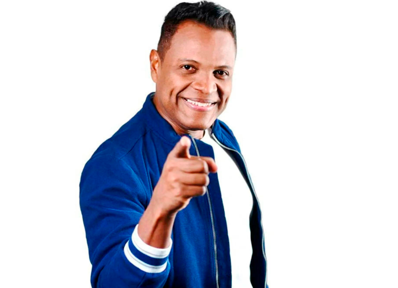 Omar Geles apunta hacia la cámara con gesto alegre, mostrando su cercanía con el público y su carisma como compositor vallenato.