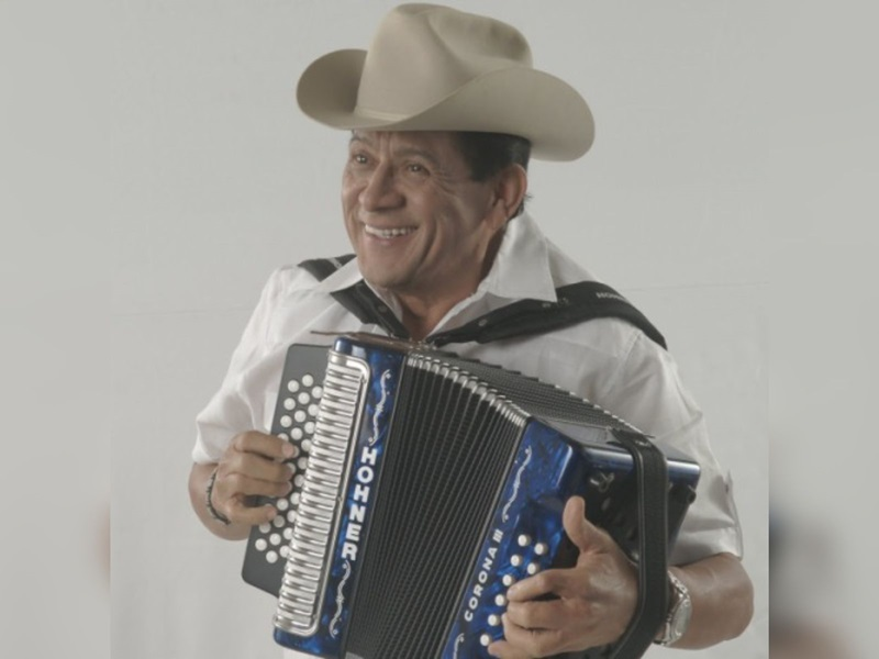Emiliano Zuleta sonriente, tocando acordeón con sombrero, mostrando su virtuosismo musical.